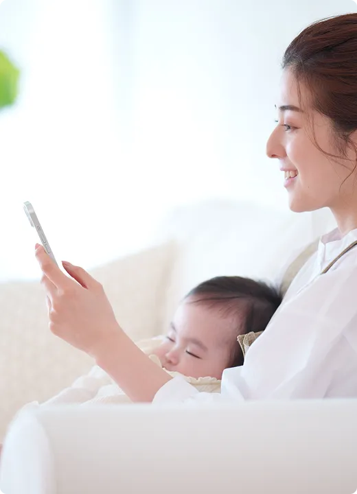子供を抱きながらスマートフォンを操作する女性